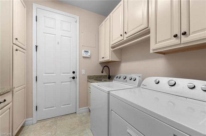 15045 Malayan Court Bonita Springs FL 34135 - Laundry room with folding area, cabinets on every wall, and a utility sink