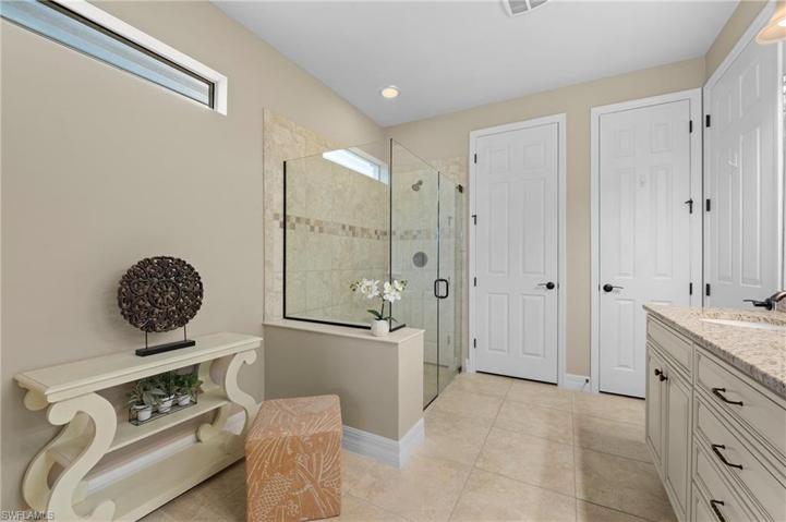 15045 Malayan Court Bonita Springs FL 34135 - Owner's bath with dual sinks, private commode, and seamless glass shower.