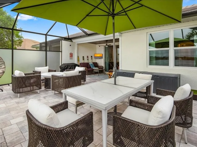 View of patio with grilling area, glass enclosure, an outdoor hangout area, and ceiling fan