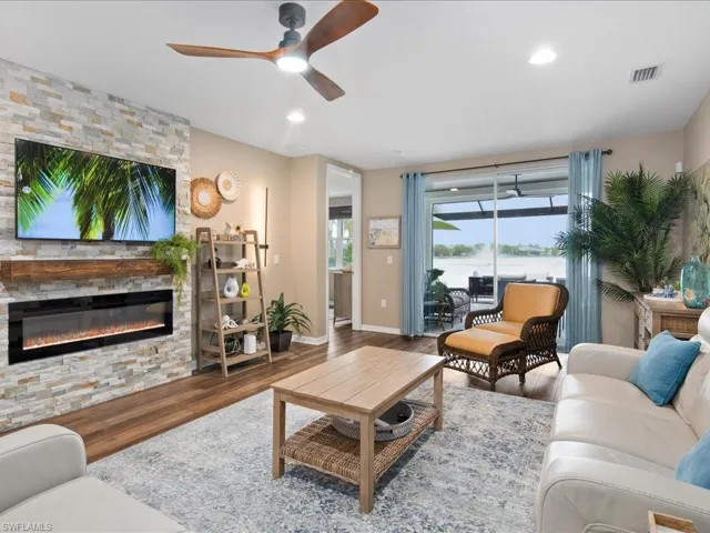 Living room featuring a water view, a fireplace, ceiling fan, and hardwood / wood-style floors