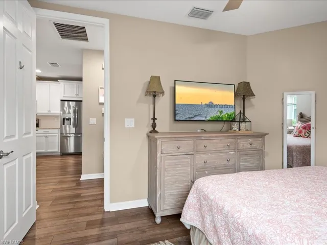 Bedroom featuring stainless steel fridge, dark hardwood / wood-style flooring, and ceiling fan