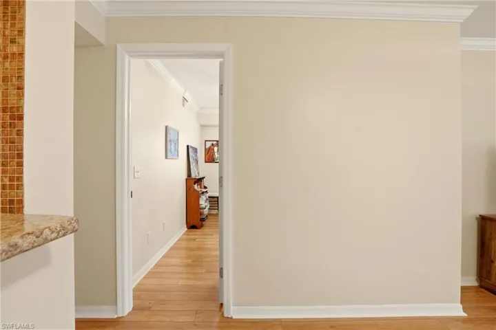 Corridor with crown molding and light wood finished floors