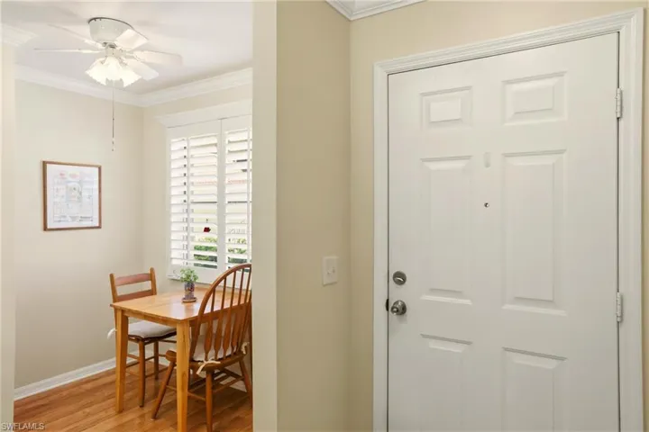 Foyer entrance with ornamental molding, light wood-type flooring, and ceiling fan