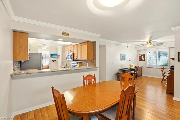 Dining area featuring ceiling fan, light wood finished floors, and crown molding