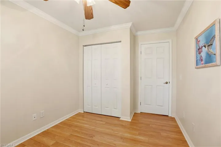 Unfurnished bedroom with ornamental molding, light wood-type flooring, ceiling fan, and a closet