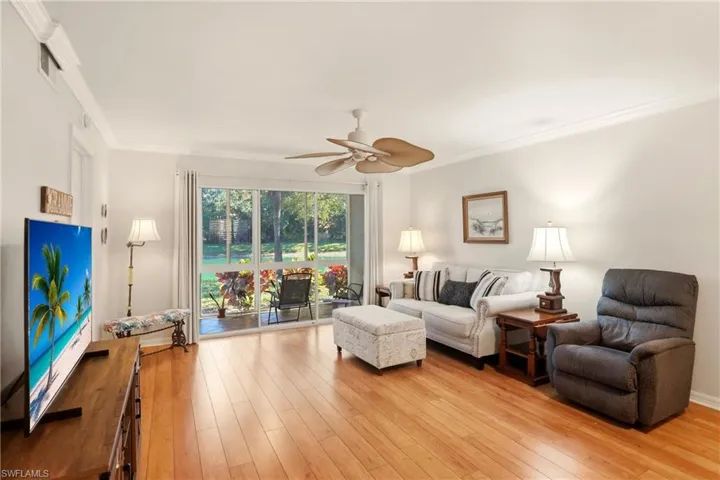 Living area featuring ornamental molding, light wood-style floors, and a ceiling fan