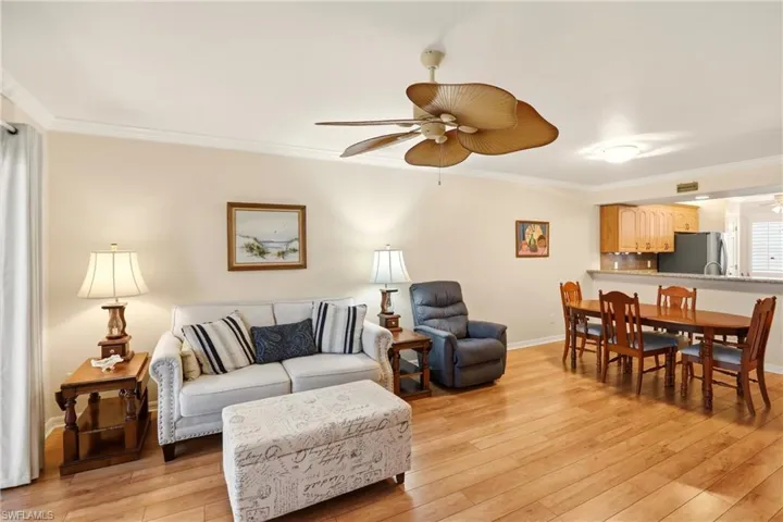 Living area featuring crown molding, light wood-style floors, and ceiling fan