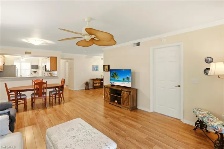 Living room with light wood-type flooring, crown molding, and ceiling fan