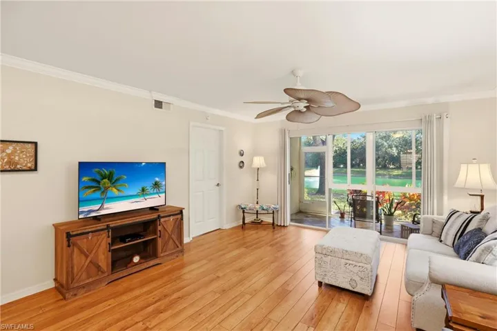 Living area with crown molding, a ceiling fan, and light wood-style floors