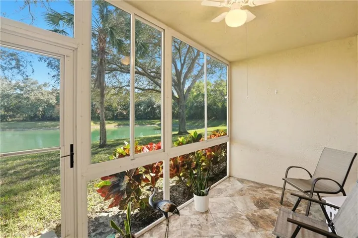 Unfurnished sunroom featuring a textured wall, a ceiling fan, a water view, and stone finish flooring