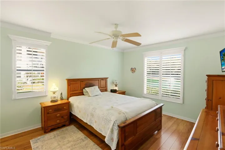 Bedroom featuring crown molding, hardwood / wood-style floors, ceiling fan, and multiple windows