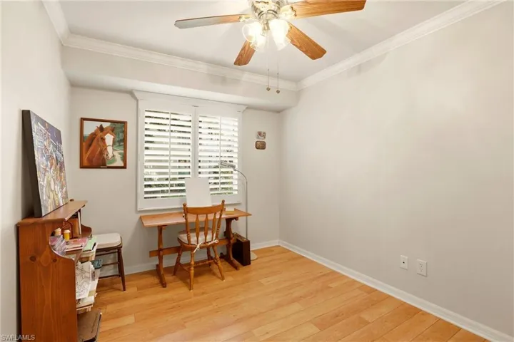 Office area featuring light wood-style floors, a ceiling fan, and ornamental molding