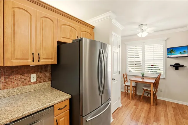 Kitchen with ornamental molding, appliances with stainless steel finishes, light stone countertops, ceiling fan, and decorative backsplash