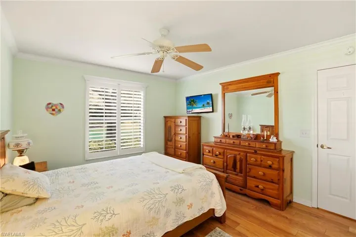 Bedroom featuring crown molding, wood finished floors, and a ceiling fan