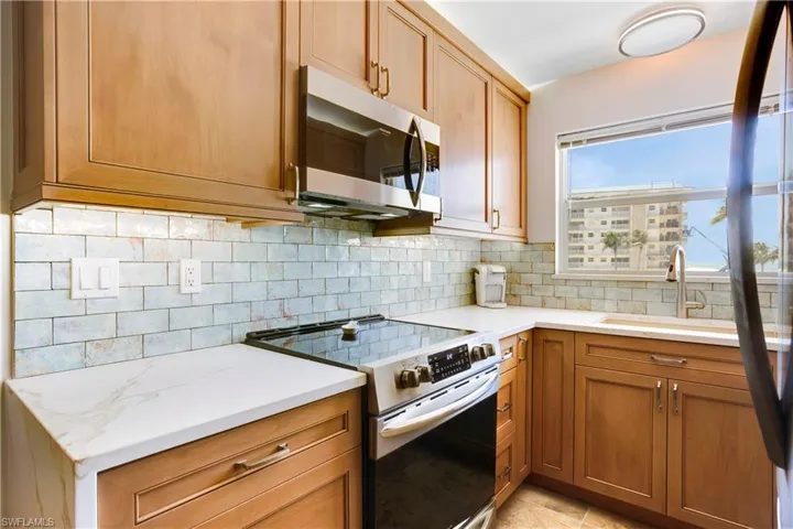 Custom renovated kitchen with wood cabinetry, quartz waterfall counters, stainless appliances.