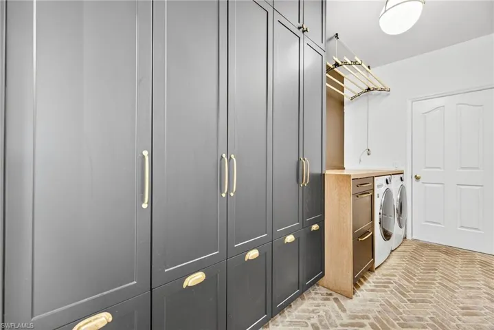 Laundry room with brick floors, front load washer and dryer, and cabinet space