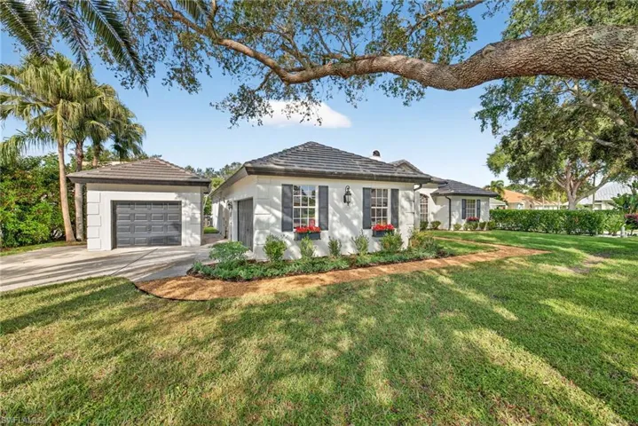 Single story home featuring a front lawn, a garage, concrete driveway, and an outdoor structure