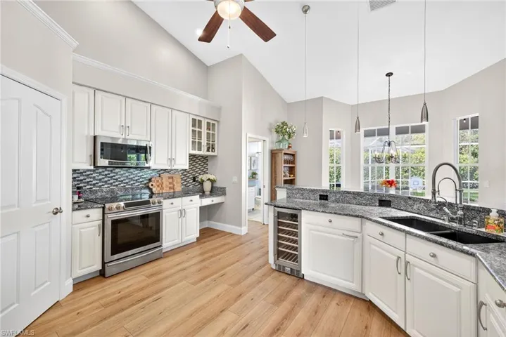 Kitchen featuring white cabinetry, glass insert cabinets, appliances with stainless steel finishes, wine cooler, and high vaulted ceiling
