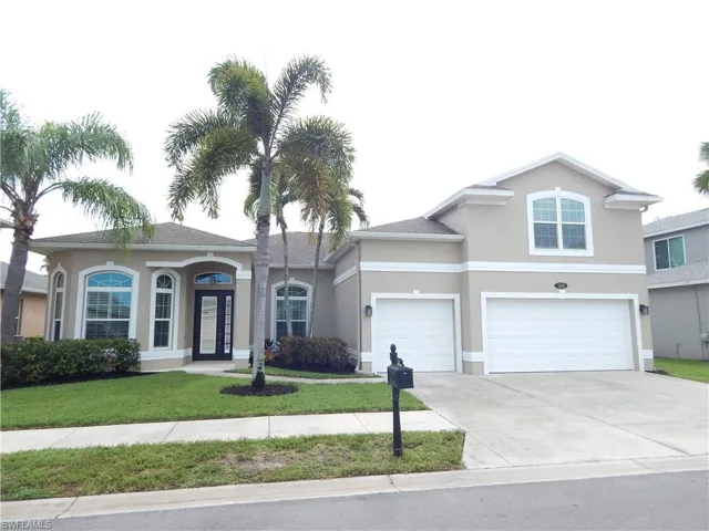 Stucco exterior with arched windows, prominent entry door, and an attached two-car garage