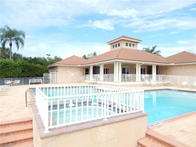 Outdoor swimming pool with integrated hot tub, surrounded by a paver deck