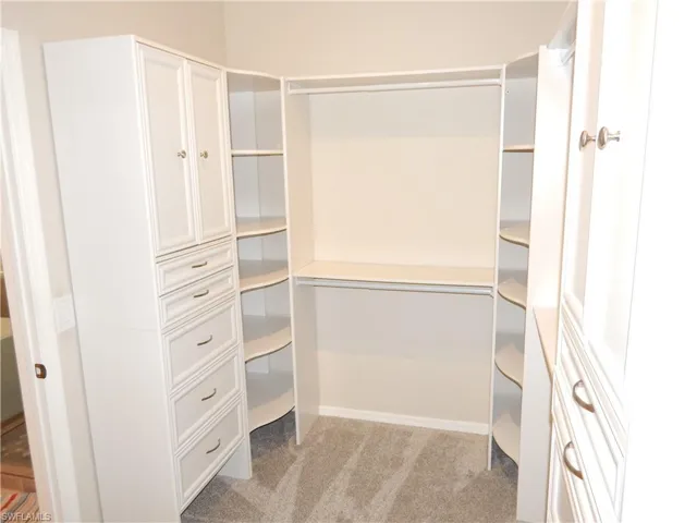 Built-in closet system featuring white cabinetry, multiple drawers, open shelving, and hanging rods