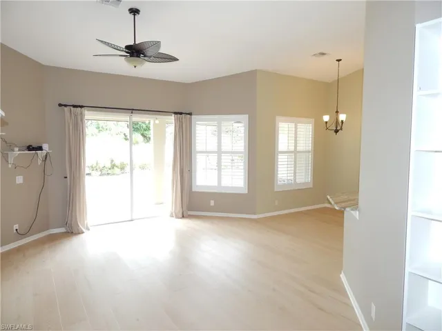 Wood-finish flooring, sliding glass door, two windows with plantation shutters, ceiling fan, and built-in shelving