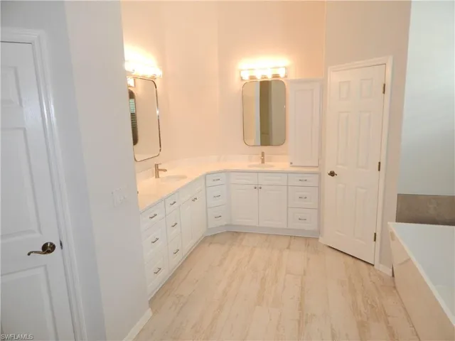 Dual vanity with white cabinetry, light-toned countertops, and rectangular mirrors