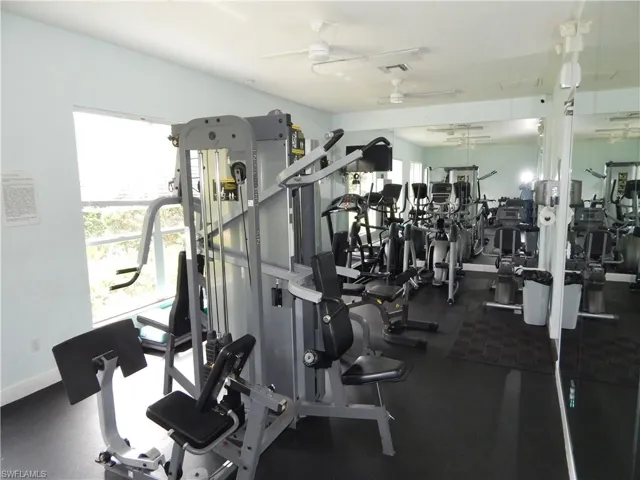 Fitness area featuring a variety of exercise equipment, wall-mounted mirrors, and rubber flooring