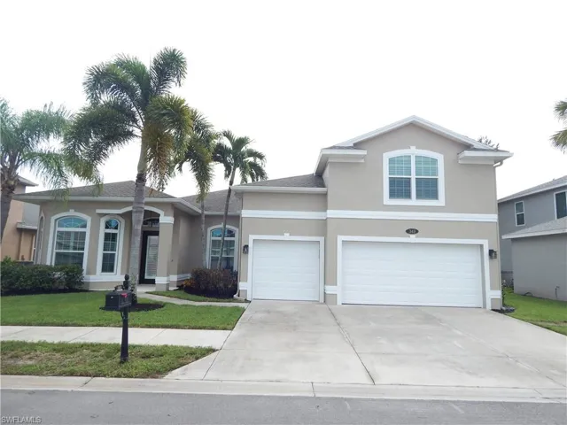 Stucco exterior with arched windows, multiple palm trees, and an attached two-car garage