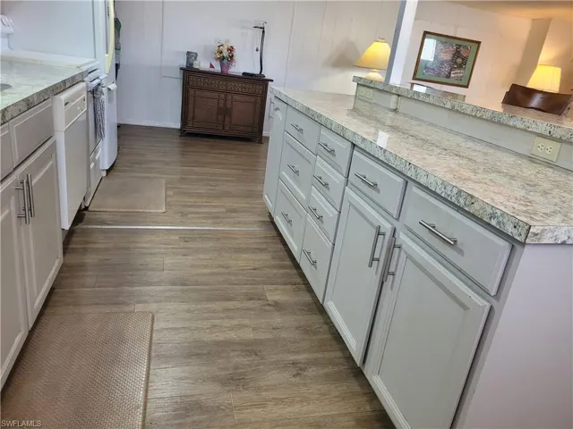 Kitchen Island with cabinetry, hanging light fixtures, and wood-style flooring