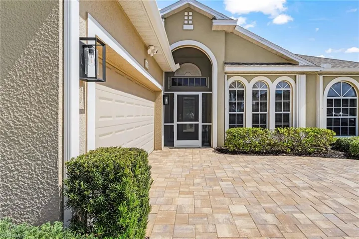 Paver driveway and walkway with stucco exterior and arched window details