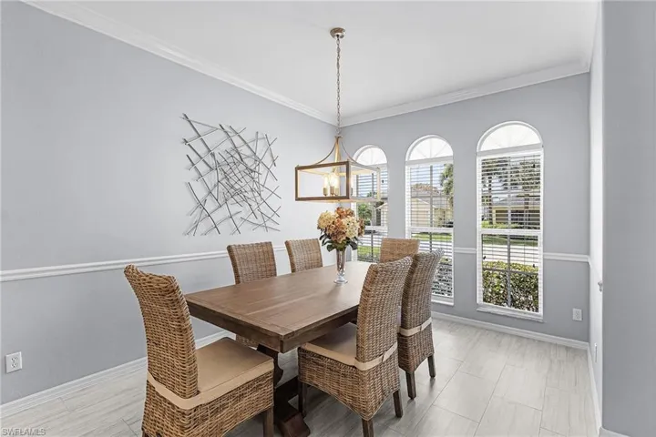 Formal dining area featuring a bronze-finish chandelier, three arched windows with horizontal blinds, and light-toned wood-finish flooring