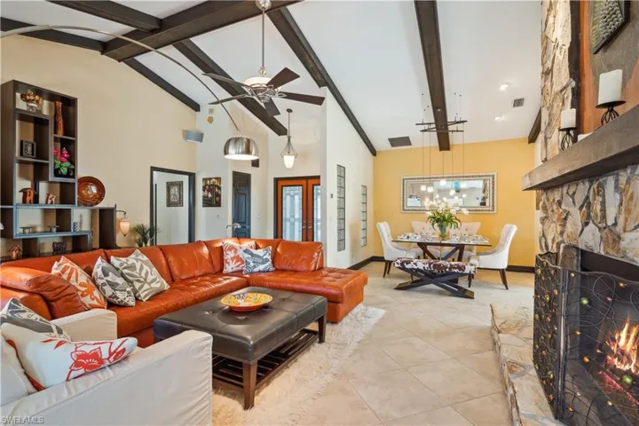 Living Area with a fireplace, ceiling fan, high vaulted and beam accent ceiling