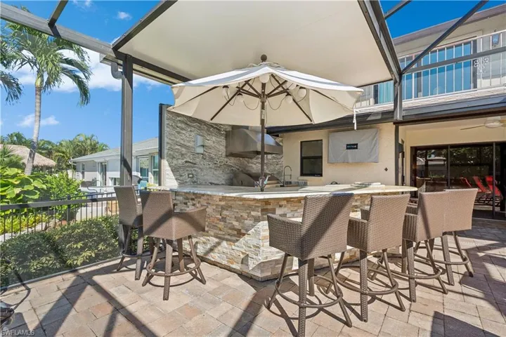 Another Part of the Outdoor Oasis - Outdoor Kitchen - stacked stone with bar -integrated firepit- flat screen TV -lighted umbrella