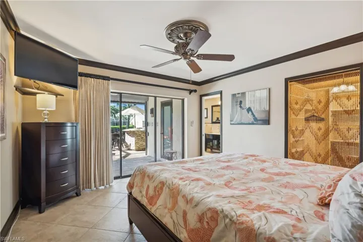 One of two Master Suites. This Suite is located on the main floor.   Bedroom with moldings, light tile patterned flooring, ceiling fan, and access to exterior.