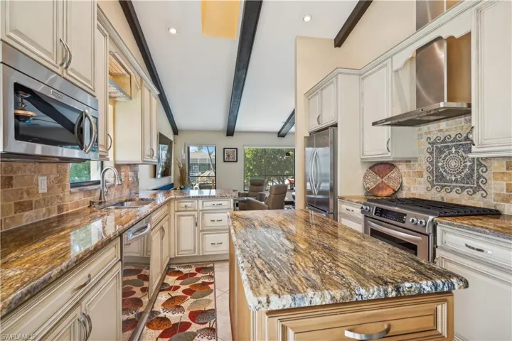 Kitchen with chimney exhaust hood, gas (propane) cooktop, and moveable kitchen island.