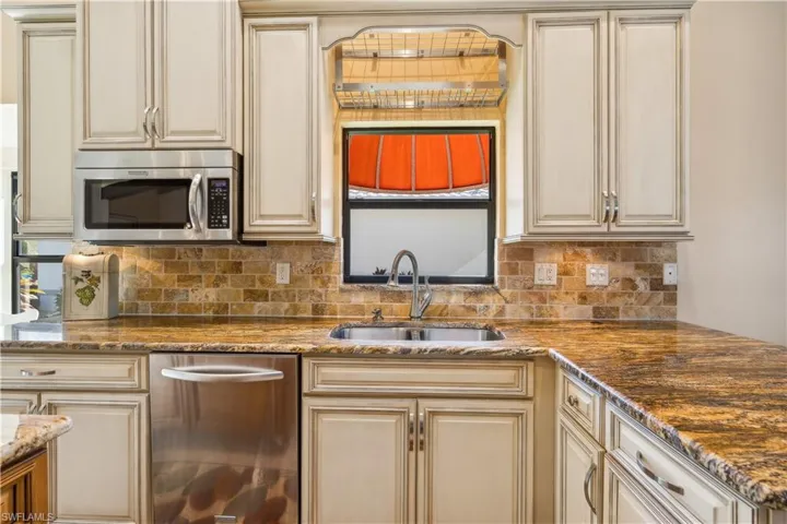 Kitchen featuring stainless appliances, granite countertops, almond shade glazed cabinets and same flooring as in the gathering spaces