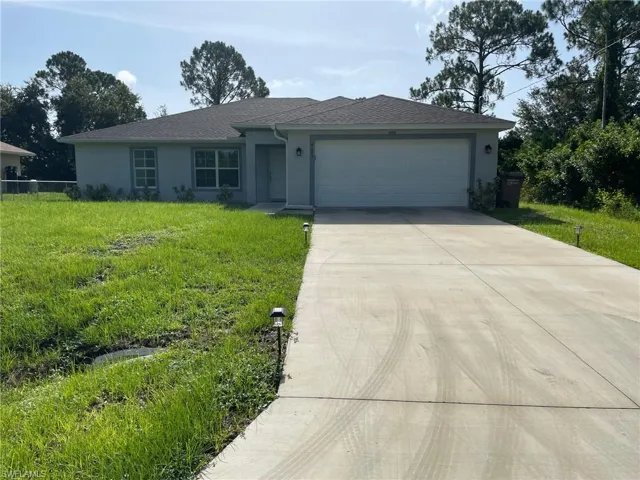 Single story home with stucco siding, driveway, an attached garage, and a front yard