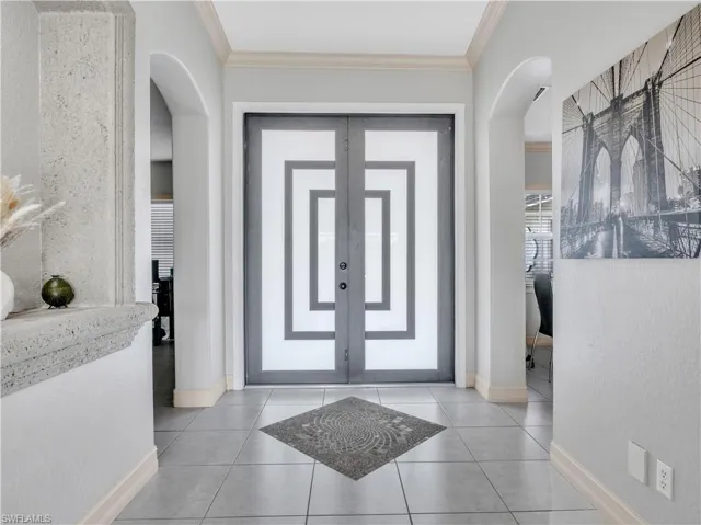 Foyer entrance with french doors, ornamental molding, and light tile patterned flooring