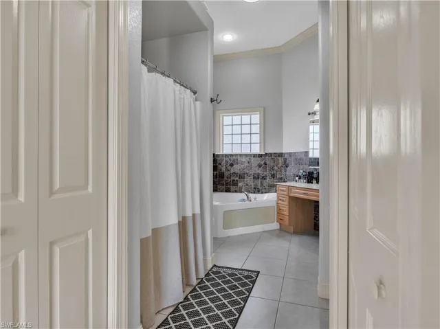 Bathroom with ornamental molding, tile patterned floors, and a tub