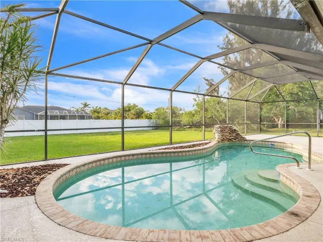 View of pool with glass enclosure and a yard