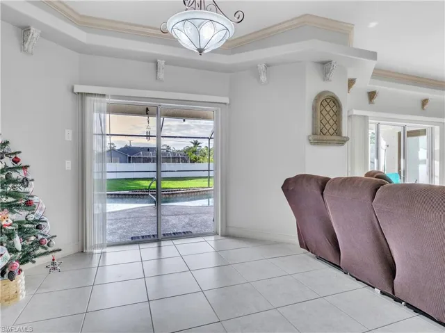 Tiled living room featuring a healthy amount of sunlight, a raised ceiling, and crown molding