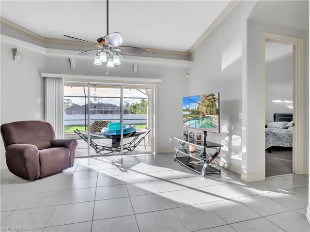 Living room featuring light tile patterned floors, ceiling fan, and ornamental molding