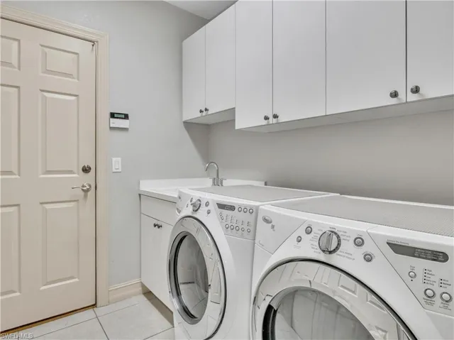 Washroom featuring light tile patterned flooring, cabinets, and independent washer and dryer