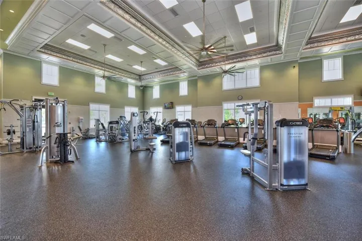 Gym featuring ceiling fan, crown molding, and a high drop ceiling