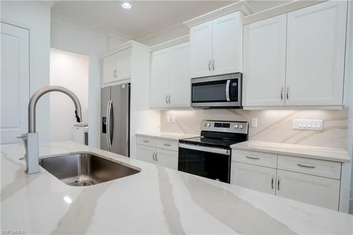 Kitchen with stainless steel appliances, white cabinetry, tasteful backsplash, light stone counters, and recessed lighting