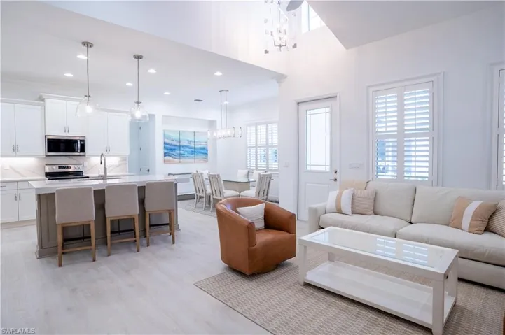 Living room featuring hanging lights, light wood finished floors, and a high ceiling