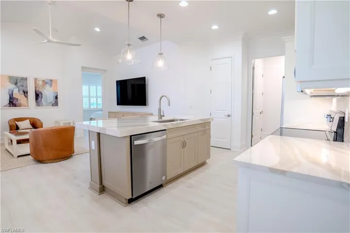 Kitchen featuring open floor plan, a center island with sink, light stone counters, stainless steel dishwasher, and range with electric stovetop