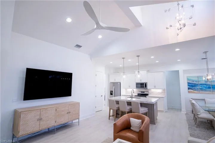 Living area with light wood-style floors, a ceiling fan, lofted ceiling, and a chandelier