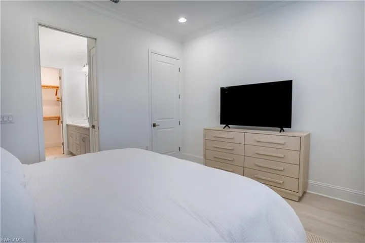 Bedroom featuring ornamental molding, recessed lighting, light wood finished floors, and ensuite bathroom